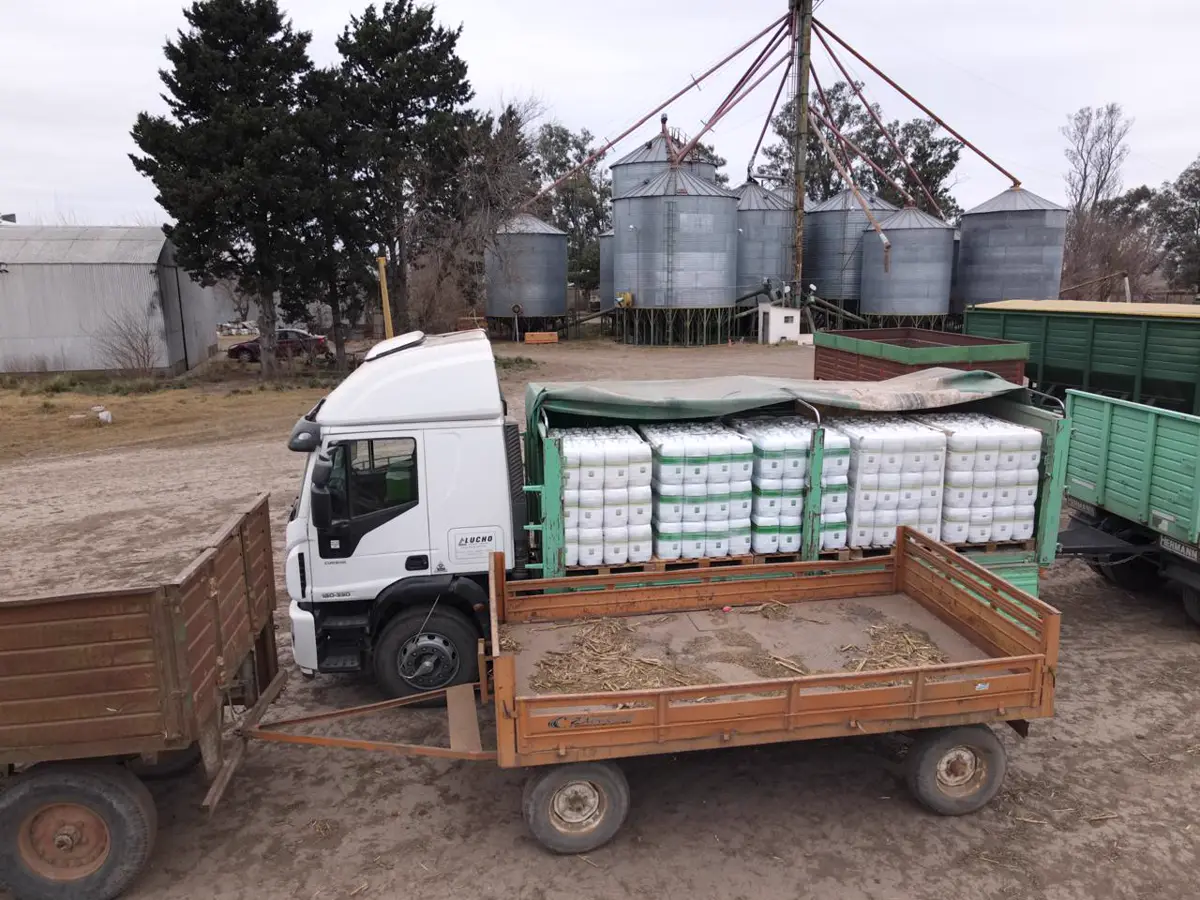 Entrega de insumos en un campo con silos de fondo